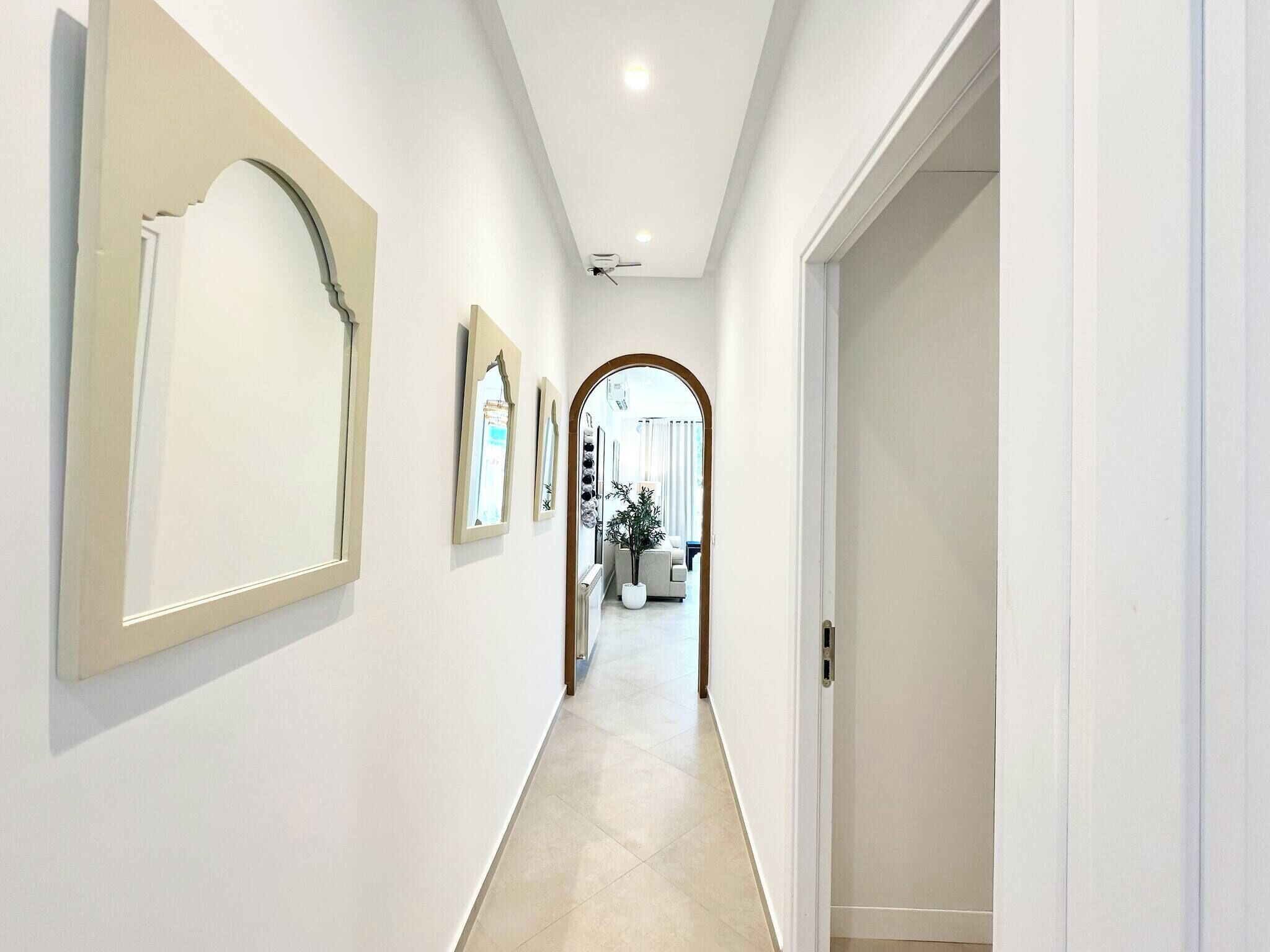 A hallway with white walls, a tiled floor, and a door on the right.