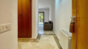 Un couloir avec une porte en bois, un radiateur et une fenêtre donnant sur un espace extérieur.