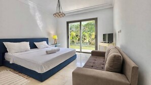 Une chambre à coucher comprenant un lit, un canapé, une lampe, un téléviseur et une grande fenêtre donnant sur un paysage verdoyant.
