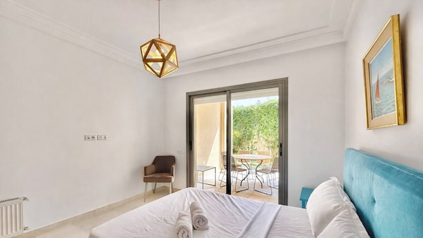 Une chambre à coucher comprenant un lit, une chaise, une table et donnant sur l’extérieur.