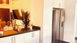 A modern kitchen with white cabinets, a black countertop, a stainless steel refrigerator, and a pendant light. - Niagara Beach Villa Your Private Caribbean Escape in Punta Cana (Punta Cana)