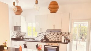 A modern kitchen with white cabinets, a central island, pendant lighting, and a view of the outdoors. - Niagara Beach Villa Your Private Caribbean Escape in Punta Cana (Punta Cana)