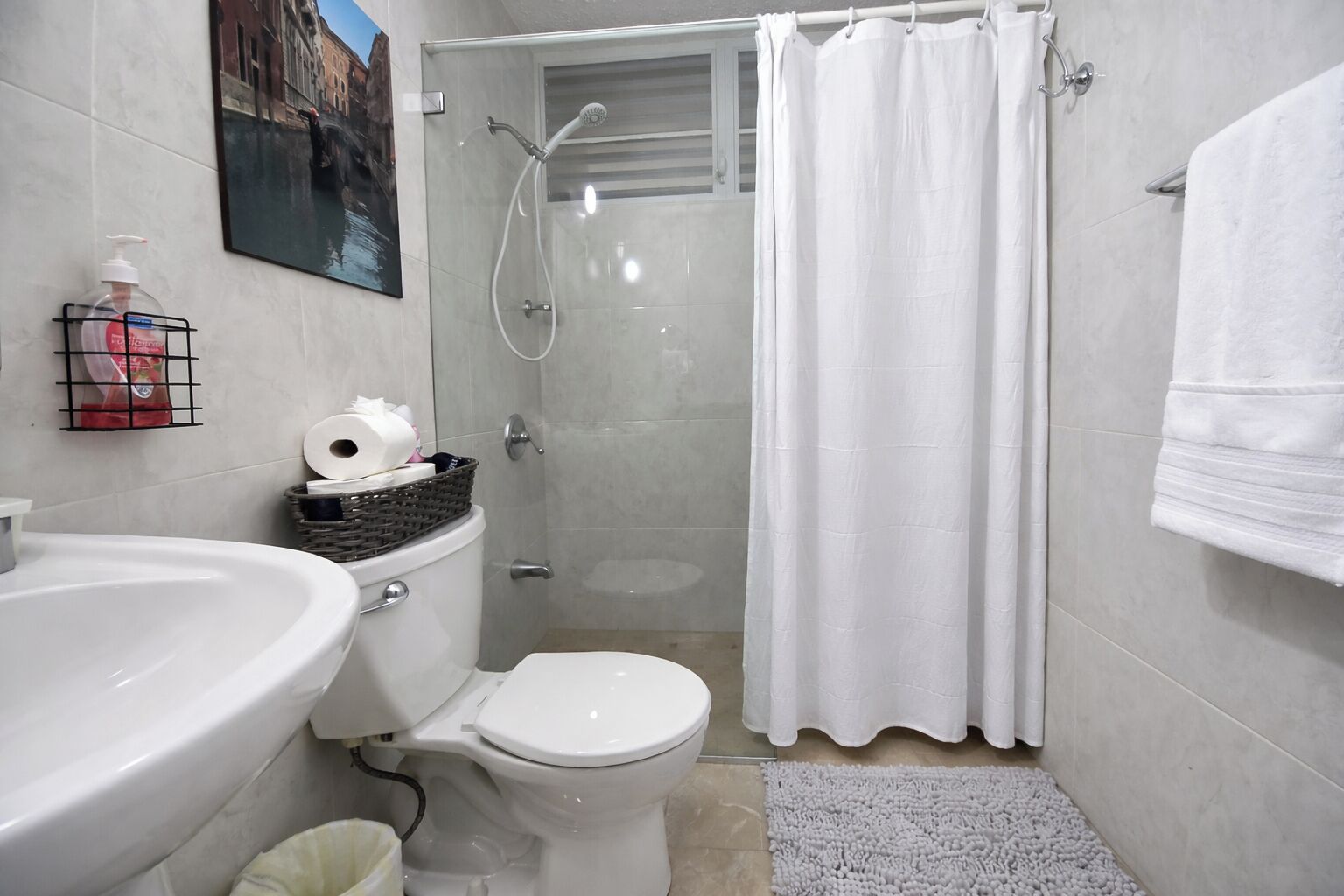 Une salle de bain comprenant des toilettes, un lavabo, une douche et un porte-serviettes.