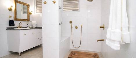 A modern bathroom with a shower, toilet, and sink, featuring a wooden mat and towel rack.