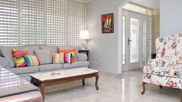 A living room with a grey sofa, colorful pillows, a white coffee table, and a floral armchair. - Modern Villa on Puerto Rico's West Coast (Mayagüez)