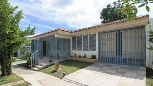A residential building with a tiled patio, a gated entrance, and a small garden area. - Modern Villa on Puerto Rico's West Coast (Mayagüez)