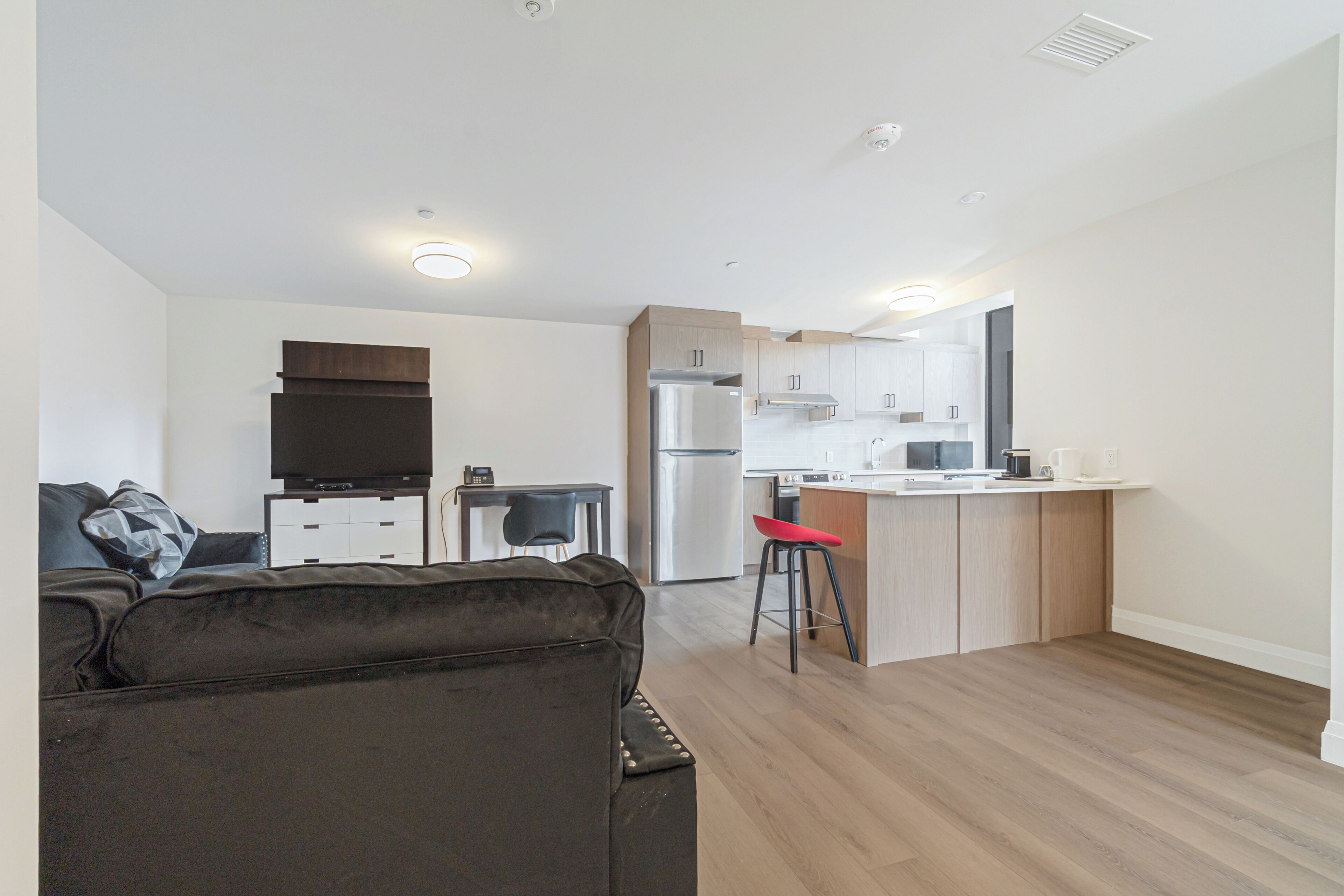 A modern apartment with a living area, kitchenette, and a small dining space.