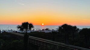 A sunset over the ocean with a wooden boardwalk and palm trees. - Stylish updated 2-bdrm/1.5 bath Condo across from Residents Beach Marco Island (Marco Island)