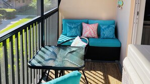 A balcony with a seating area, a table, and a view of a building. - Stylish updated 2-bdrm/1.5 bath Condo across from Residents Beach Marco Island (Marco Island)
