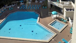 Un hotel con piscina, vista sulla spiaggia e diversi balconi.