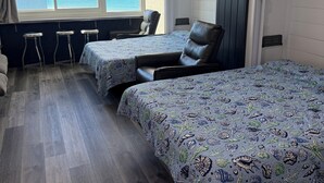 Una stanza con due letti, una finestra vista mare e un soffitto con pannelli in legno.
