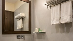 A bathroom with a large mirror, a white sink, and a towel rack. - Barak Glow Stay (Silchar)