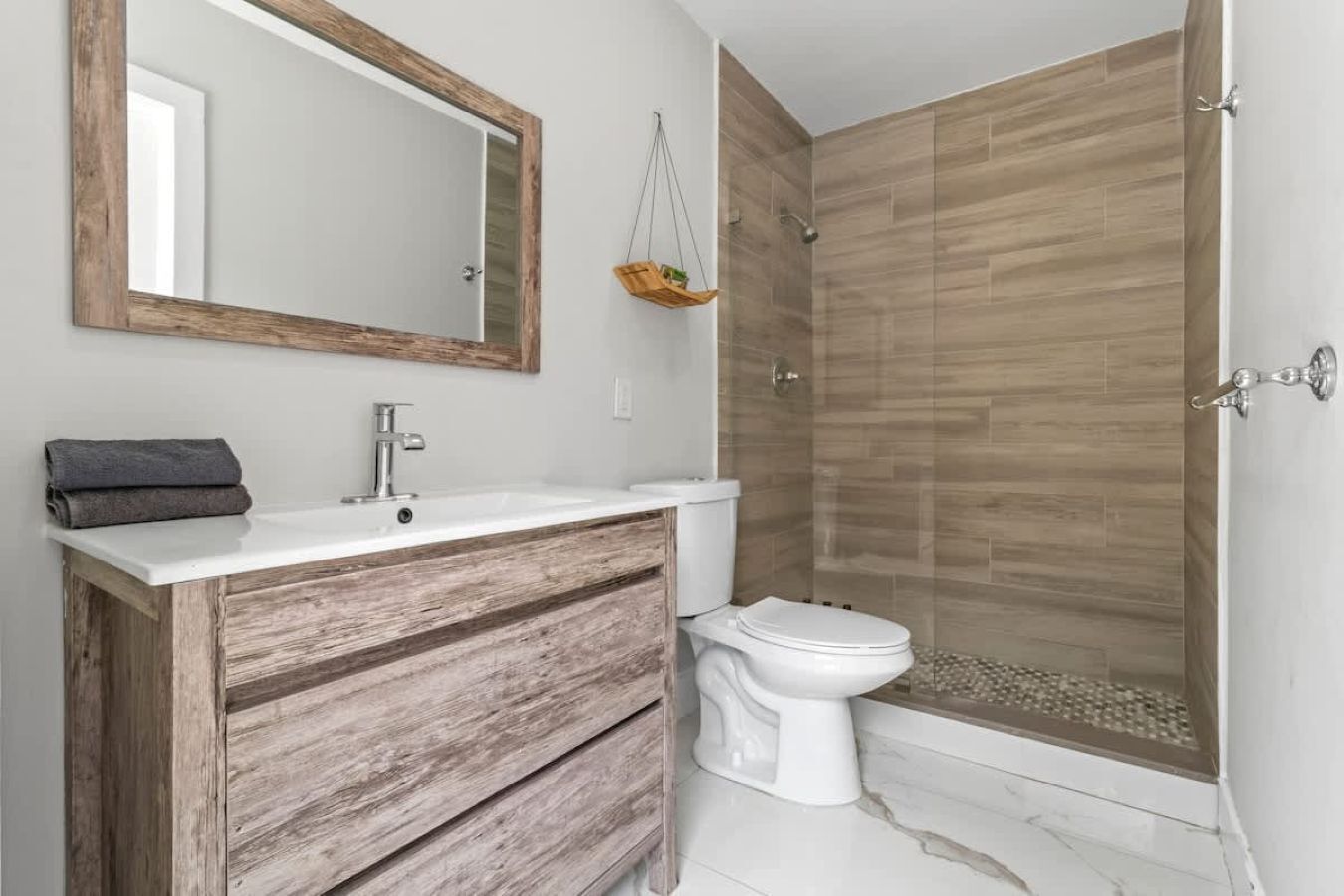 A bathroom with a wooden vanity, a white sink, a toilet, and a shower with wooden walls.