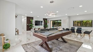 Ein moderner Poolbereich im Innenbereich mit Billardtisch, Sitzgelegenheiten und einem Fernseher.