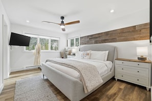 A bedroom with a bed, bedside tables, a ceiling fan, a TV, and a window. - The Alpine Atelier I 4BR Townhome Near Shuttle Stop (Vail)