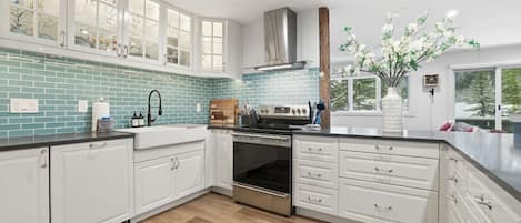 Una cocina moderna con armarios blancos, horno de acero inoxidable y un backsplash de azulejos azules.