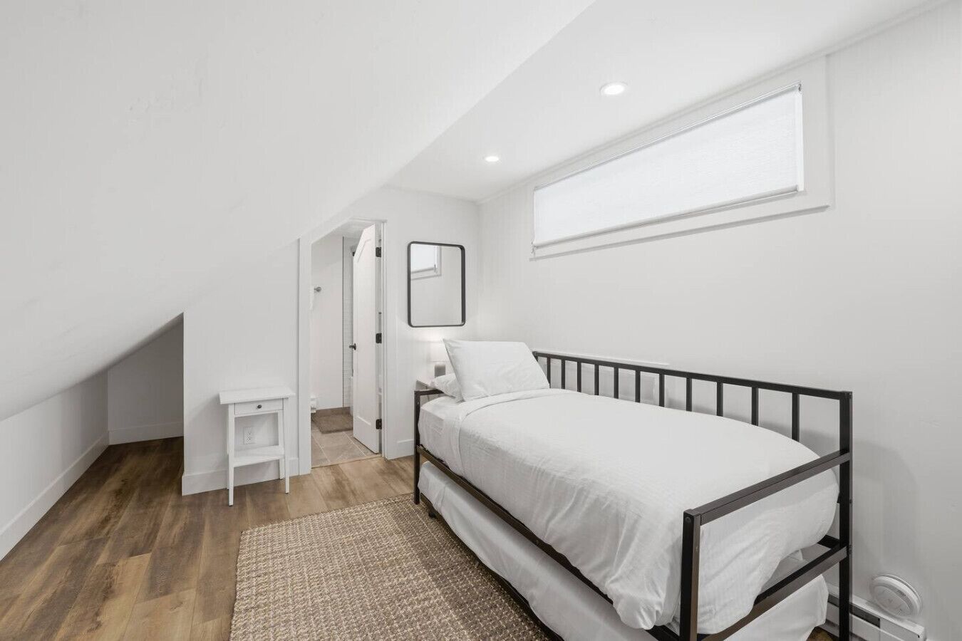 A bedroom with a bed, bedside table, and a window.