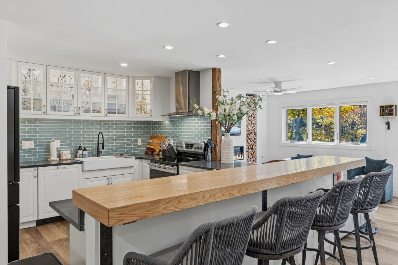 A modern kitchen with a central island, bar stools, and a view of the outdoors.