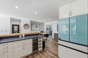 A modern kitchen with white cabinetry, a black countertop, and a glass-fronted refrigerator. - The Alpine Atelier I 4BR Townhome Near Shuttle Stop (Vail)
