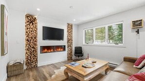 Un salon moderne avec une cheminée, un téléviseur à écran plat, une table basse en bois et un canapé.