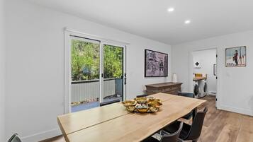 A modern kitchen with a wooden table, chairs, and a view through the glass door.