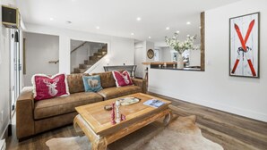 Un salon moderne avec un canapé en cuir marron, une table basse en bois et un tapis à poils longs blanc.