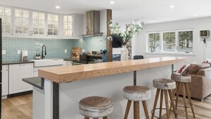 Une cuisine moderne dotée d’un îlot central, de tabourets de bar et offrant une vue sur l’extérieur.