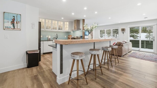 Une cuisine moderne dotée d’un îlot central, de tabourets de bar et d’une grande fenêtre offrant une vue sur l’extérieur.