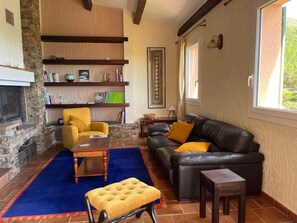 A living room with a fireplace, a sofa, a yellow armchair, and a coffee table. - Villa Rhea - Pool - Panoramic Views of the Sea and Hills (La Londe-les-Maures)