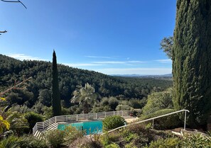 A pool with a white railing, surrounded by greenery and overlooking a forested valley. - Villa Rhea - Pool - Panoramic Views of the Sea and Hills (La Londe-les-Maures)