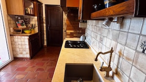 Una cocina con un lavamanos grande, estufa y armarios de madera.