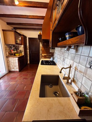 A kitchen with a large sink, stove, and wooden cabinets. - Villa Rhea - Pool - Panoramic Views of the Sea and Hills (La Londe-les-Maures)