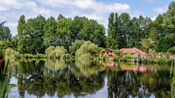 A tranquil lake with a gazebo and a small building surrounded by lush greenery. - Cottage Parks La Comtesse (Bélus)