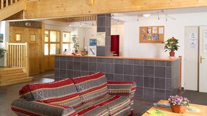 A reception area with a wooden reception desk, a sofa, and a staircase.
