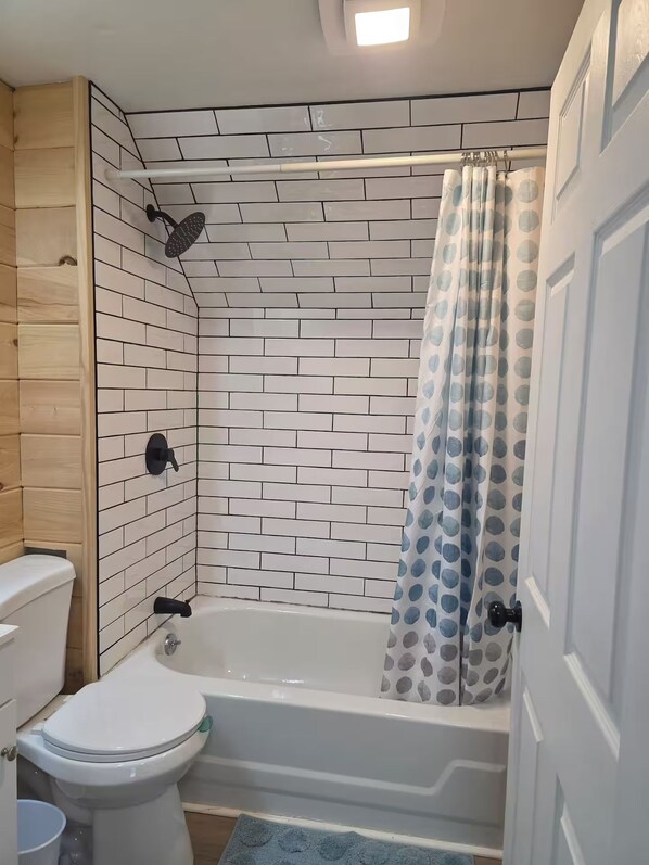 Un baño con inodoro blanco, bañera y cortina de ducha.