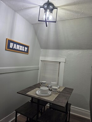 Ein Essbereich mit einem Tisch für vier Personen, einer Deckenleuchte und einem Schild mit der Aufschrift 'FAMILY'.