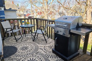 A patio with a grill, two chairs, and a patterned rug. - Cozy 2-bed apt in Rochester near UR Campus, Highland Park, and Downtown (Rochester)