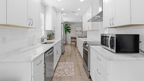 Una cucina moderna con mobili bianchi, un forno a microonde e un pavimento in legno.