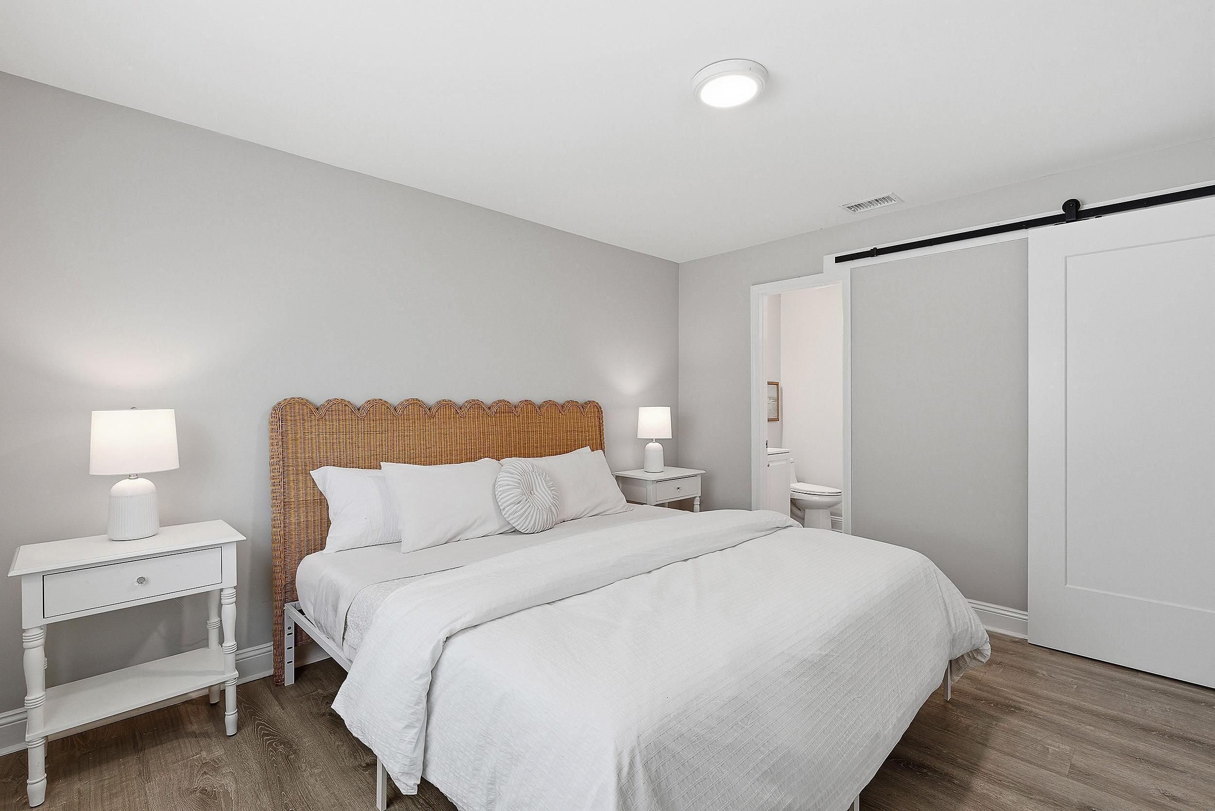 Quarto com cama, mesas de cabeceira, abajur, guarda-roupa e luminária de teto.