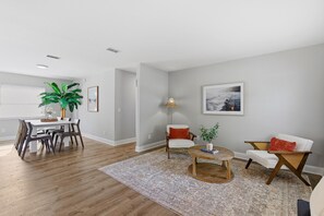 A modern living room with a dining area, a round coffee table, and a large plant. - Orange Coast Getaway (Port Orange)