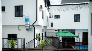 Un patio con piscina, una sombrilla verde y una pequeña palmera.
