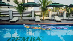 Una piscina con sillas de descanso y sombrillas, identificada como 'GEMBA HOTEL & RESORT'.