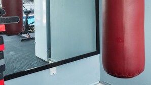 Un gimnasio con dos sacos de boxeo rojos, un espejo grande y una ventana con vista al exterior.