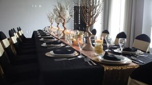 A long dining table set for a formal meal with chairs, plates, cutlery, and a centerpiece. - 1BR Two-Queen Suite + Sofa Bed in St. Pete (St. Petersburg)