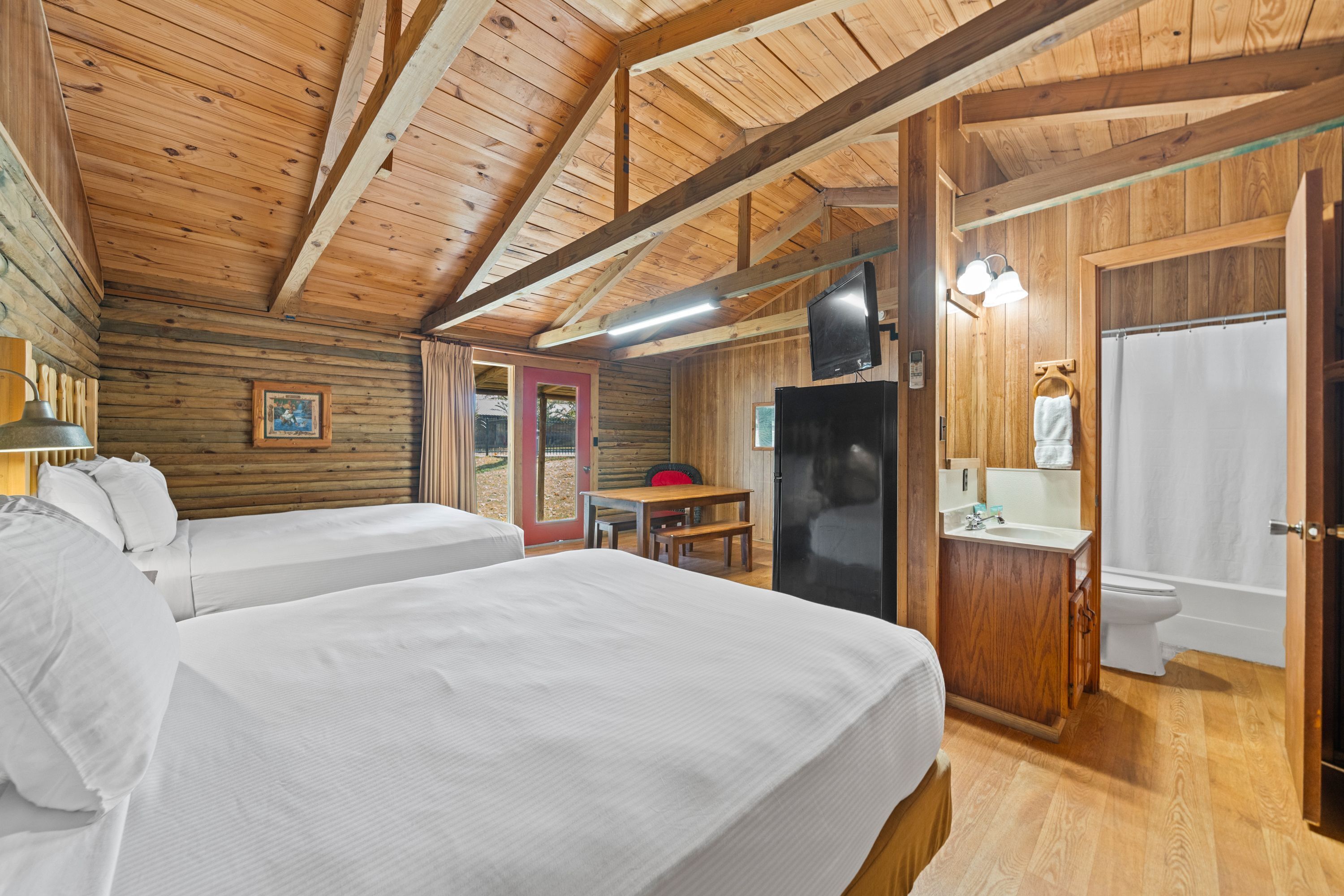 Une cabine équipée de deux lits, d’un plafond en bois, d’une télévision, d’un lavabo et d’une porte donnant accès à une salle de bain.
