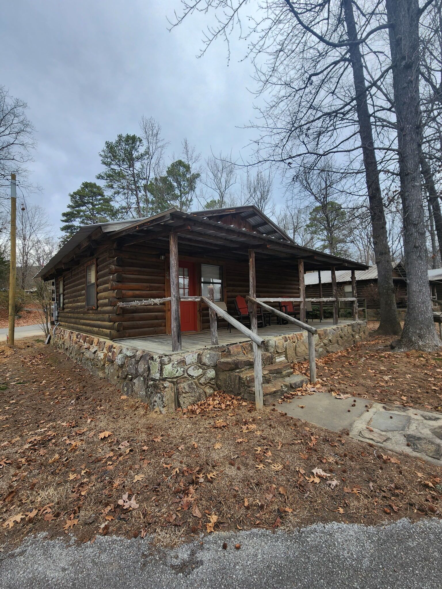 A rustic log cabin with a stone foundation, a porch, and a staircase leading to the entrance.