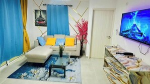 Ein Wohnzimmer mit Sofa, Couchtisch, Fernseher und Dekorationselementen.