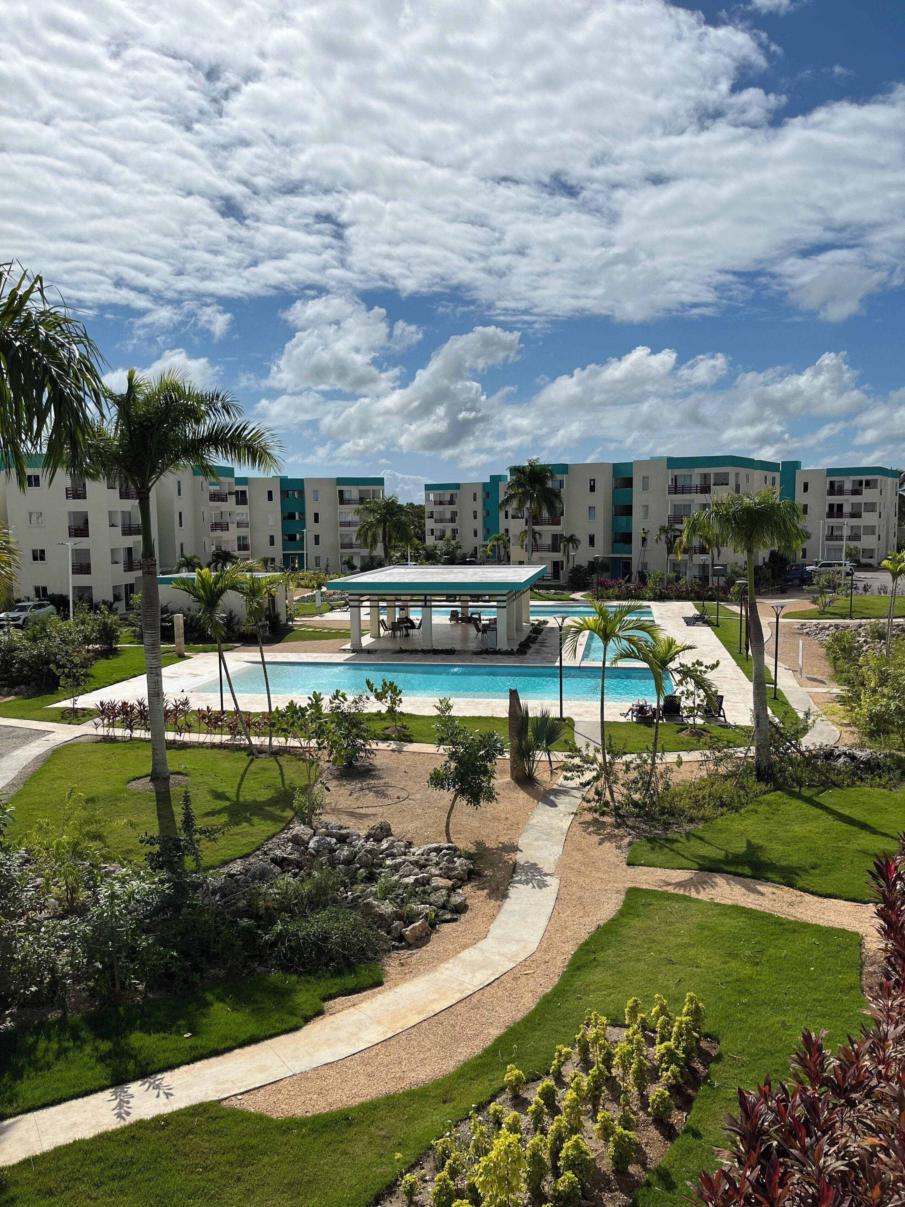 Un resort con piscina, palmeras y una zona cubierta.