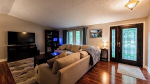 A living room with a sofa, TV, entertainment unit, and a door with glass panels. - Gorgeous 3-bedroom house with 2nd living rooms in charming Roswell (Roswell)
