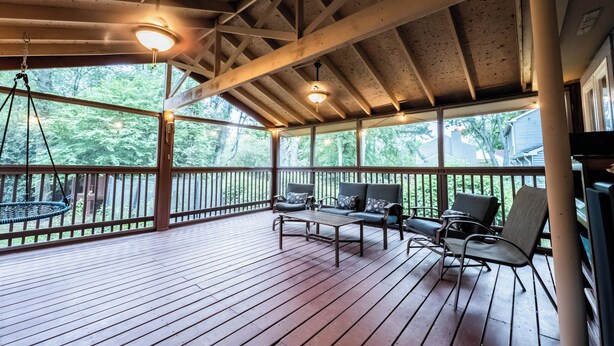 A covered porch with wooden beams, a hanging chair, and a sofa with cushions. - Gorgeous 3-bedroom house with 2nd living rooms in charming Roswell (Roswell)